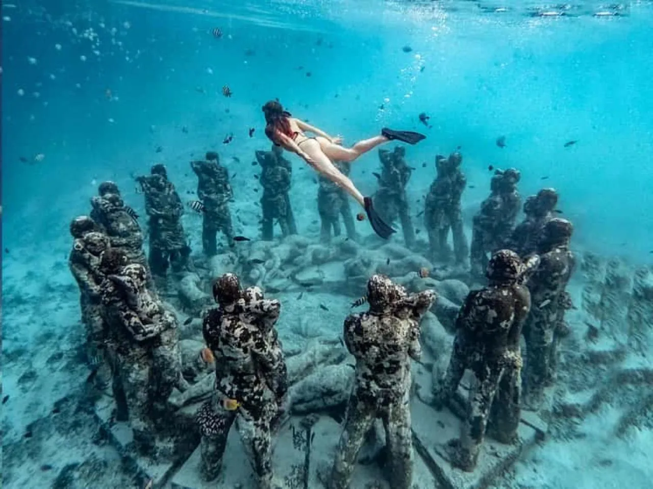 A freediver above the ring of underwater statues off Gili Meno